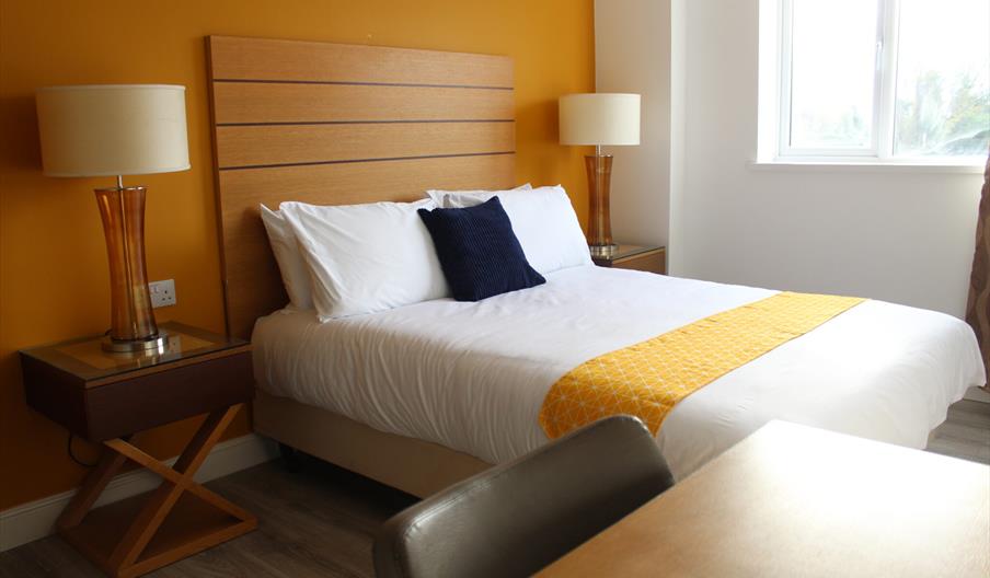 Room with double bed and desk and bedside cabinets.