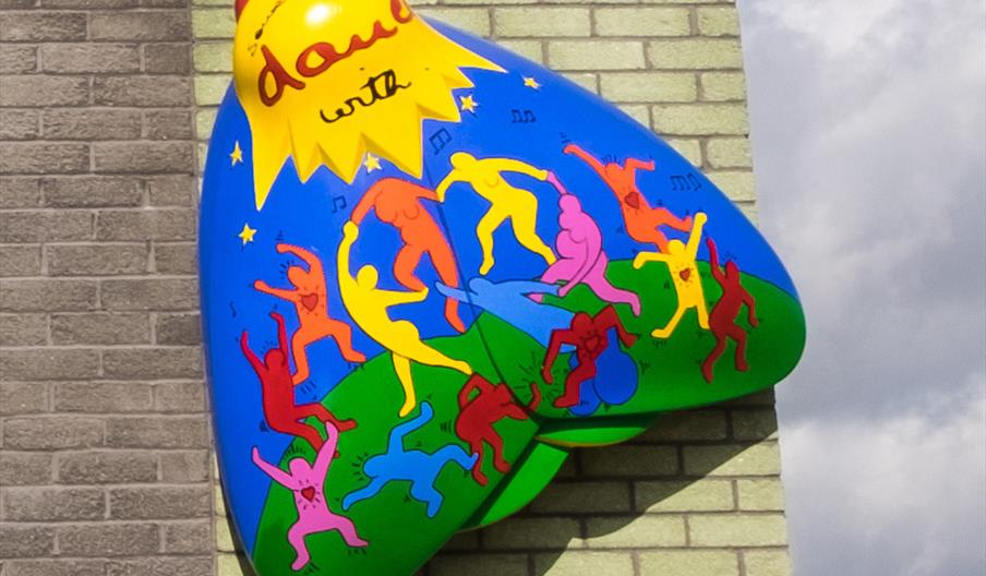 A brightly coloured large sculpture of a moth on the side of a building.