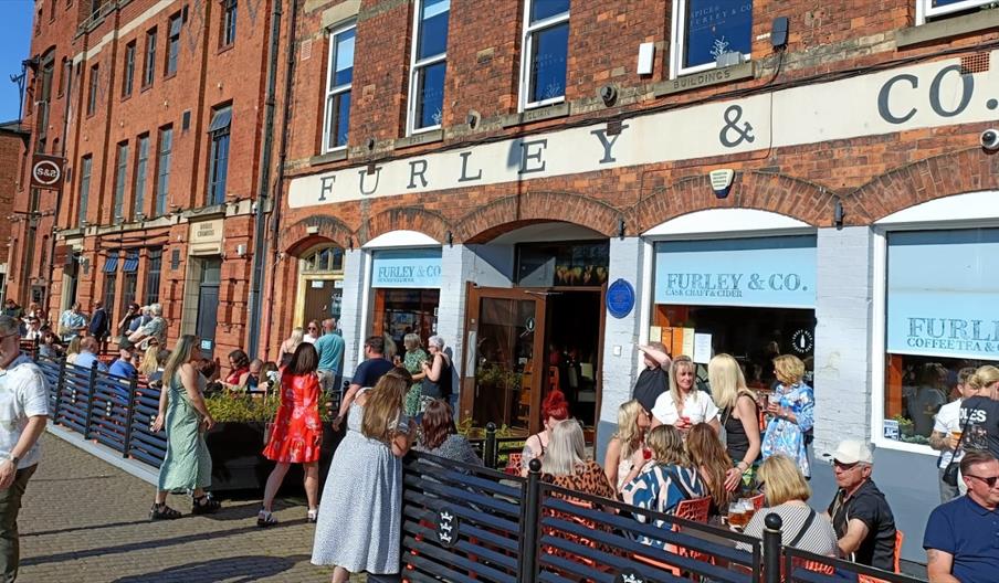 Visitors seated outside Furley & Co at Hull Marina on a sunny day, with busy outdoor dining and waterfront views.