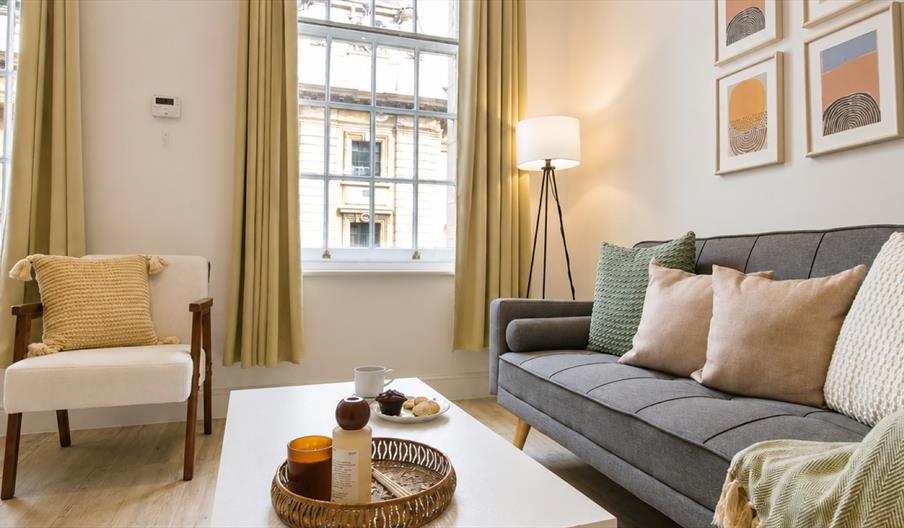 Stylish and modern living area within a premium city-centre holiday rental in Hull, featuring a grey sofa, comfortable armchair, contemporary artwork,