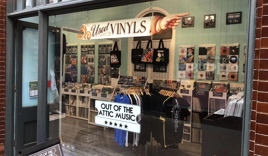 A glass fronted window which show what the inside of the shop , which has tshirts, records and other merch on display.