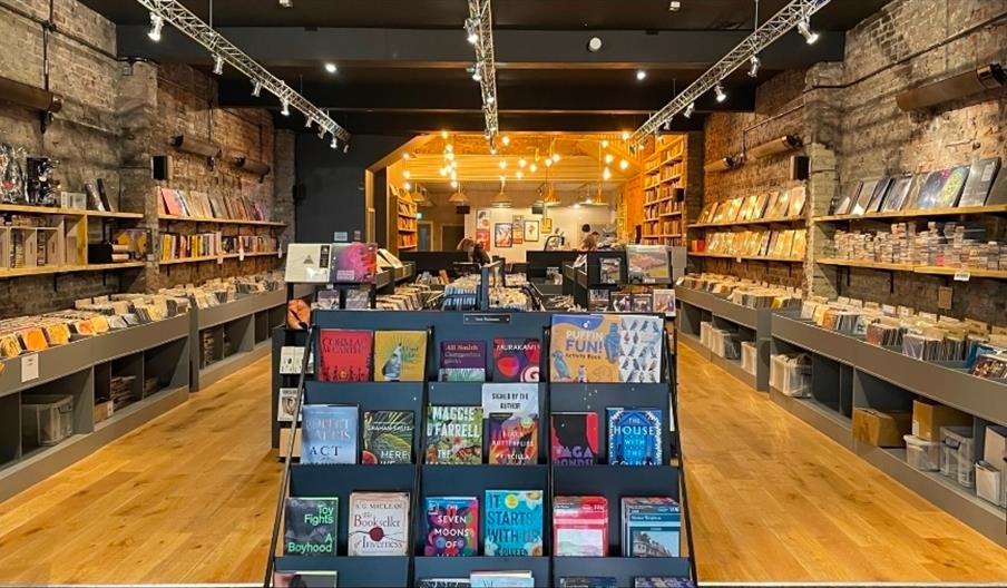 Interior of a Wrecking Ball Press book shop and cafe  in Hull, featuring exposed brick walls, wooden flooring, and shelves filled with vinyl records a