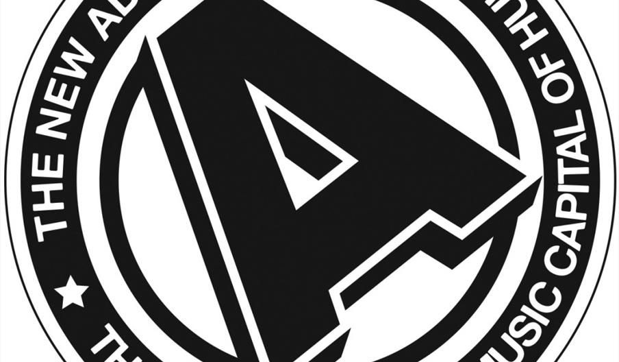 Black and white circular logo for The New Adelphi Club, featuring a stylised letter "A" in the centre. The outer ring contains the text “THE NEW ADELP