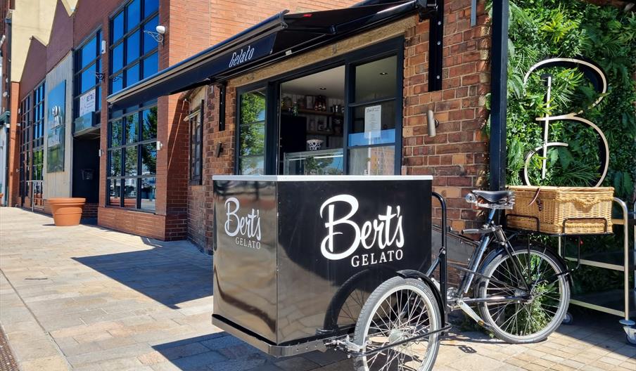 Exterior of low level red brick building with black canopy and black vintage tricyle.