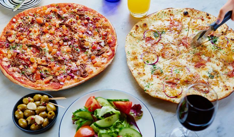 The image shows the exterior of a brightly lit restaurant at night named "Khan's," with illuminated signage above the entrance and colorful menu poste
