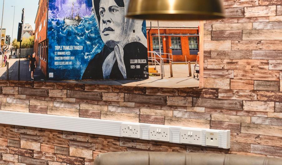 Interior of restaurant with wooden tables, leather chairs and copper pendant lamp.