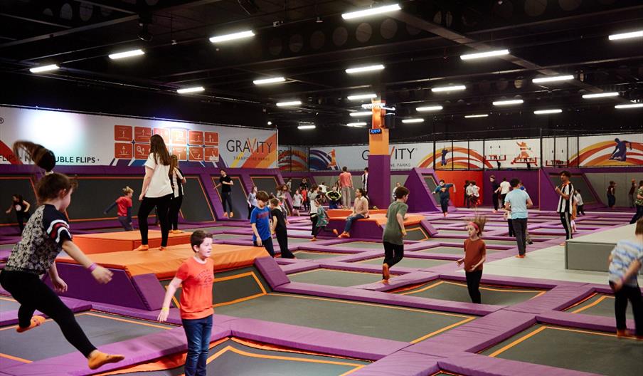 A large room filled with trampolines and children jumping on them.