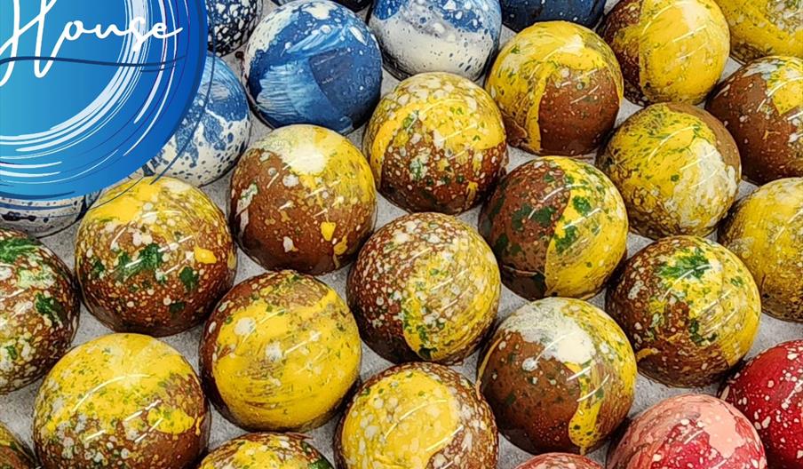 An array of multicoloured, dappled chocolate domes lined up in an orderly fashion.