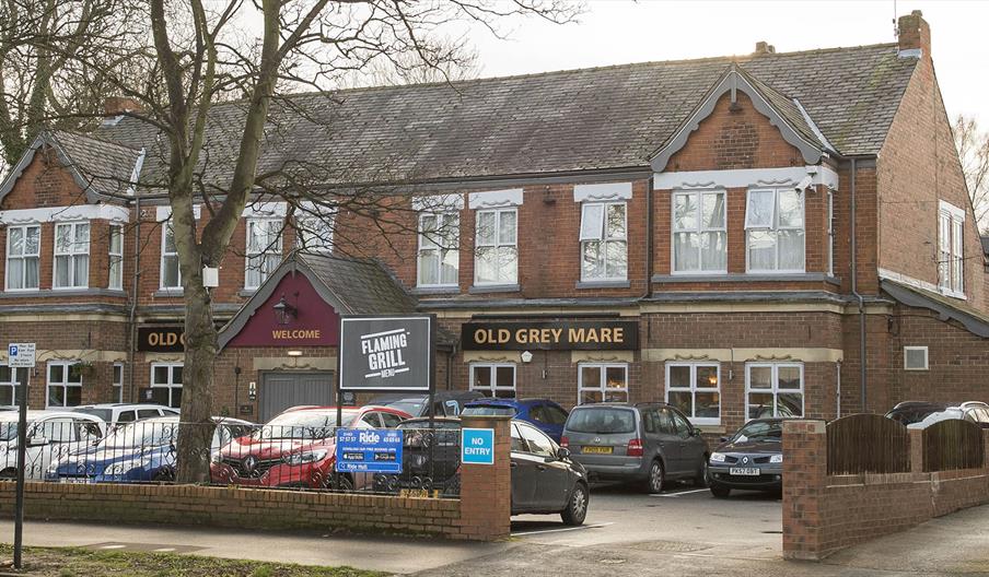 Outside of a red bricked building with a car park at the front and main entrance to the pub & hotel.