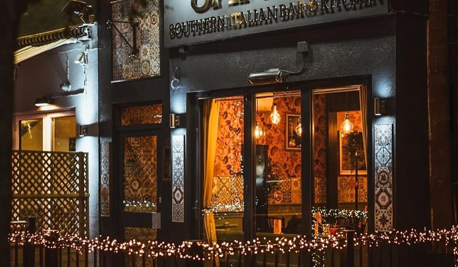 A warmly lit Southern Italian restaurant named "Santis," featuring decorative lights and inviting decor in a cozy evening setting.