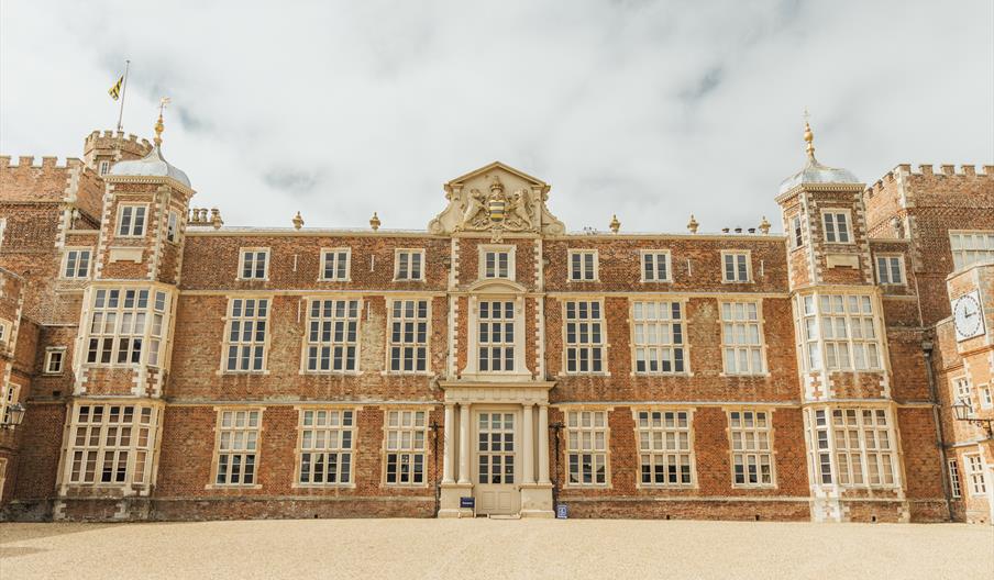 The large, symmetrical historic mansion of Burton Constable Hall in Skirlaugh, with red brick walls and many tall, white-paned windows sits at the end