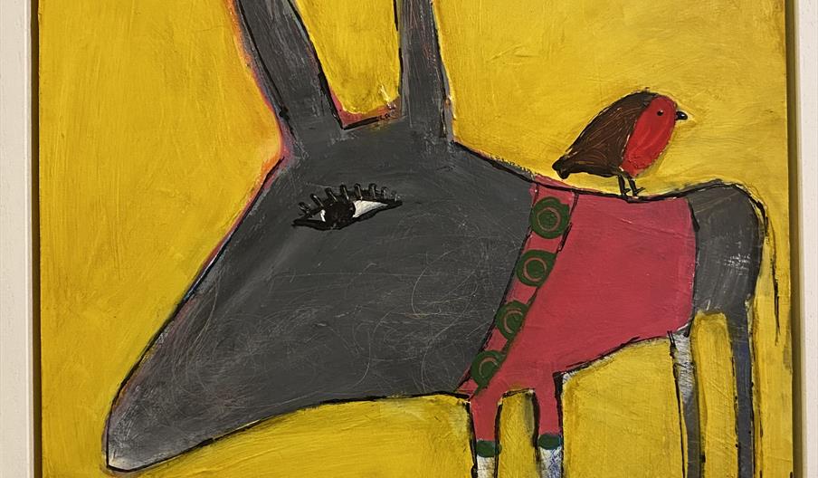 A colorful painting of a donkey with a gray face, tall ears, and a pink blanket, with a small red bird standing on its back, set against a bright yell