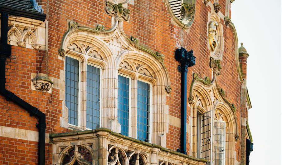 Exterior of The Punch Hotel. Close-up view of a historic brick building with ornate stone trim, arched windows, intricate balcony details, and decorat