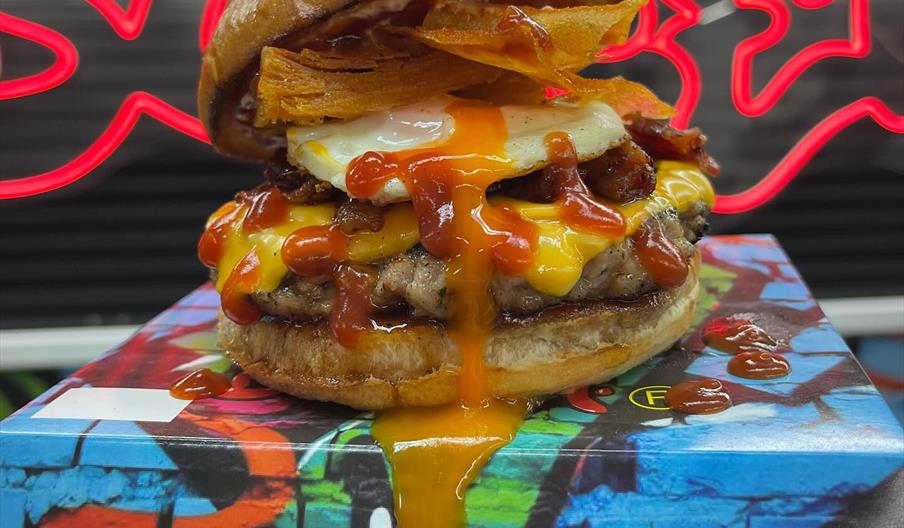 Burger with cheese, bacon and a runny egg on a block covered in graffati.