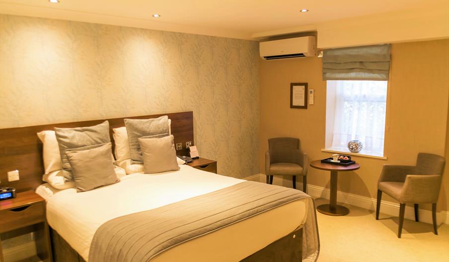 Bedroom with double bed, two armchairs and a small round table.