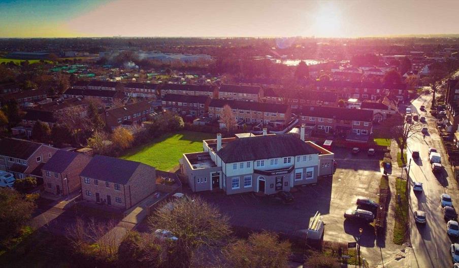 A rack of glazed, barbecued ribs sits on a wooden surface, topped with chopped herbs and chili flakes, with glowing embers and sparks in the air, evok