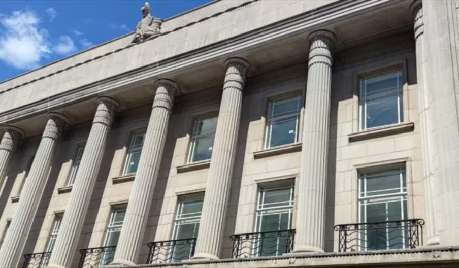 A white building with several pillars and windows against the backdrop of a blue sky.