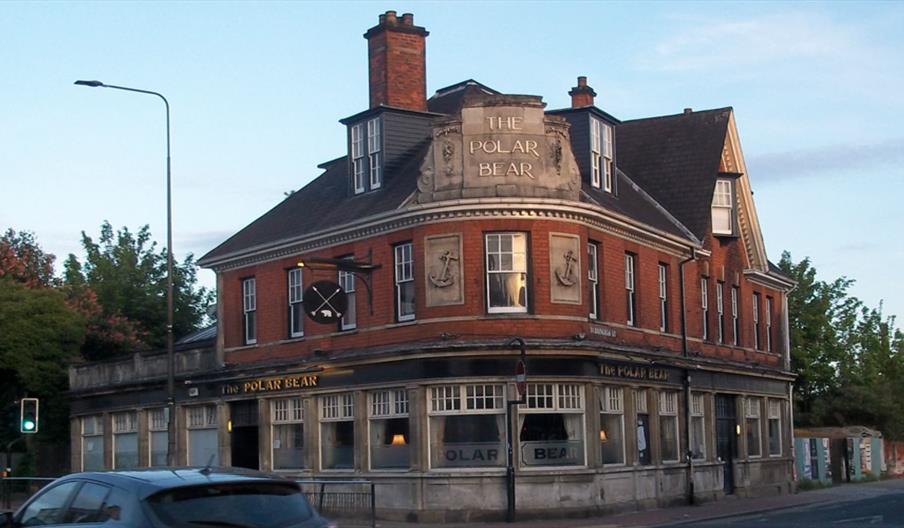 A large brick building with “The Polar Bear” sign prominently displayed at the top, featuring large windows, decorative anchors on the facade, and a t