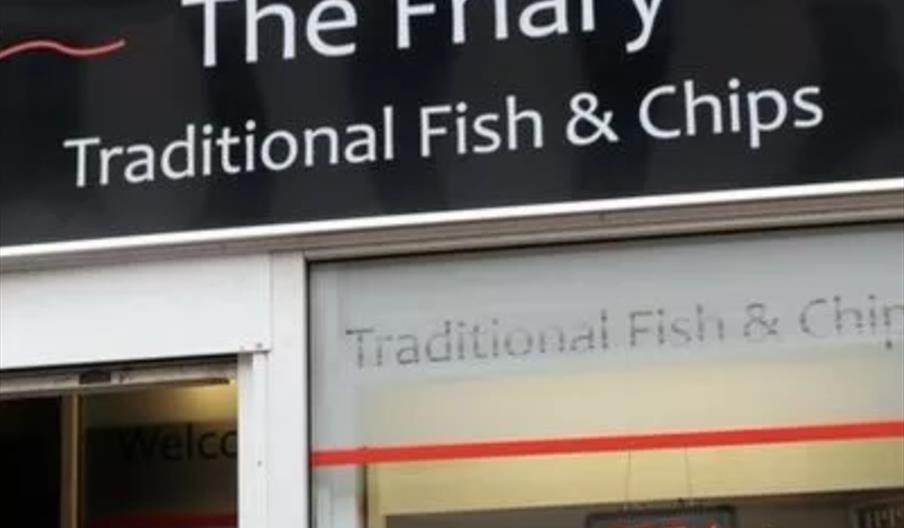 The image shows the storefront sign of a fish and chip shop called "The Friary," with the words "Traditional Fish & Chips" in large white letters on a