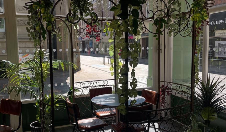 Interior with metal pagoda covered in fake plants, round table and chairs