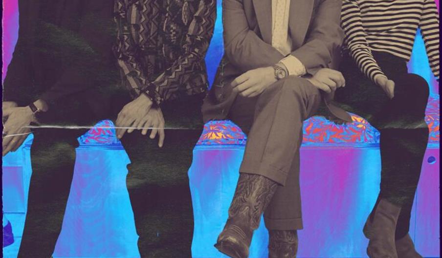 Poster for the band Aircooled featuring a black-and-white photo of four band members sitting in a row, with a colorful pink, red, and blue gradient ba