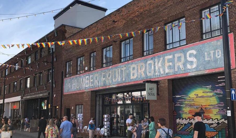 A red brick building with a large, faded sign reading "The Humber Fruit Brokers Ltd". Underneath, a smaller sign reads 'Art & Soul', next to a store t