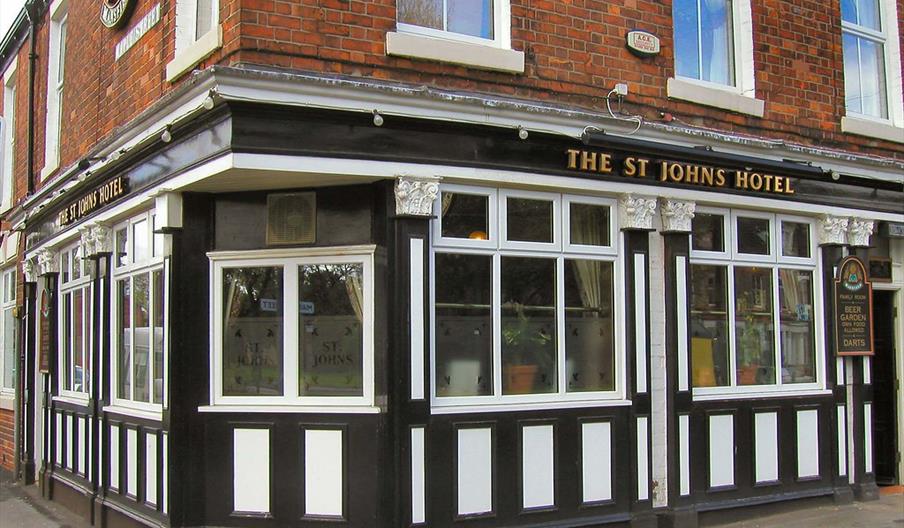 The exterior corner of The St. Johns Hotel, a two-story brick building with large, white-paned windows and black-and-white trim. There are signs above