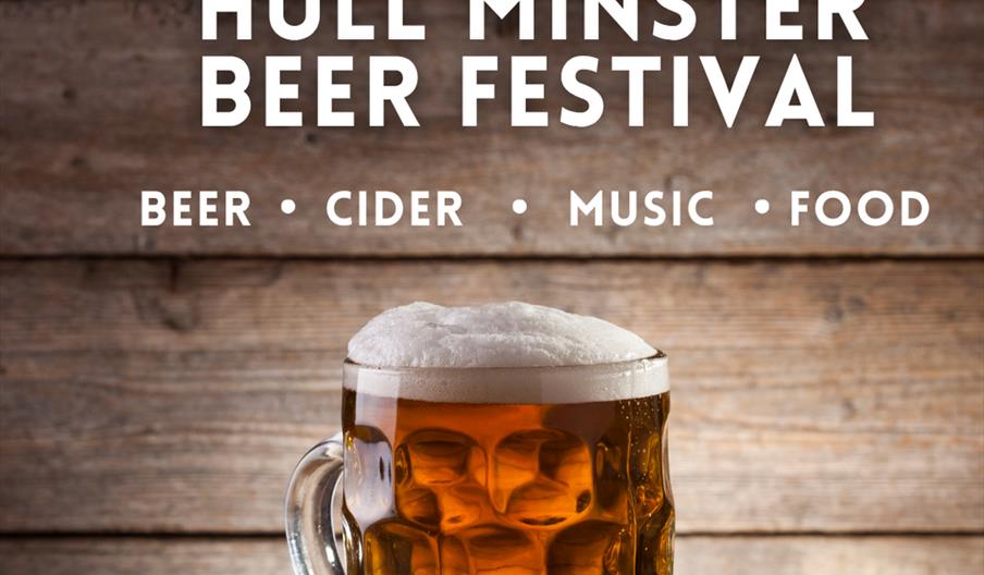 A pint glass of beer with a foamy head sits on a wooden table, with text above reading "Hull Minster Beer Festival" and details below stating "Beer •