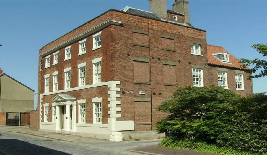 The exterior of Blaydes House in Hull, a brick building with white windows and two palisades framing the front door.