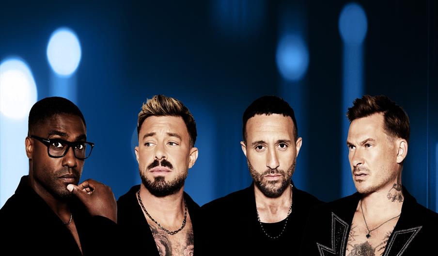 Blue's band members stand side by side against a dark background with blue light orbs, each wearing black clothing and looking in different directions