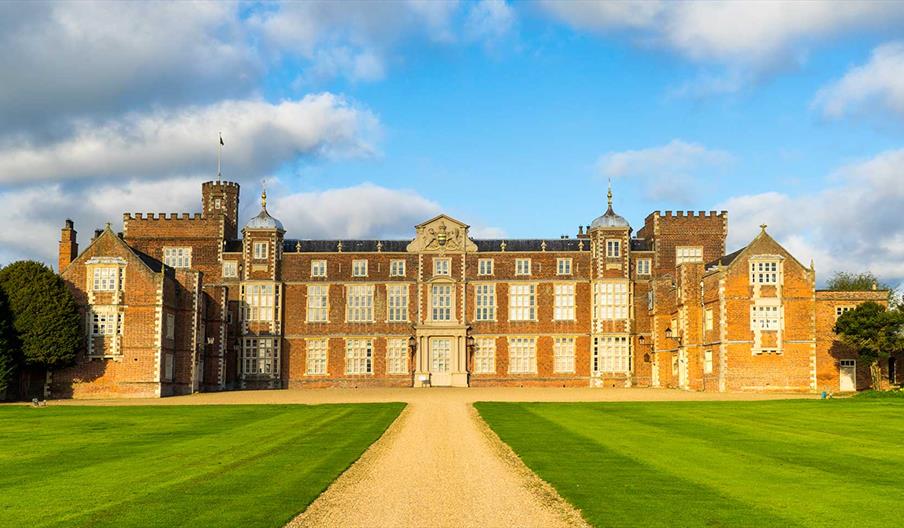 The large, symmetrical historic mansion of Burton Constable Hall in Skirlaugh, with red brick walls and many tall, white-paned windows sits at the end