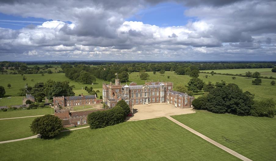 The exterior of Burton Constable Hall in Skirlaugh. It is a large stately home made of brickwork and white windows, with a view along the pathway lead