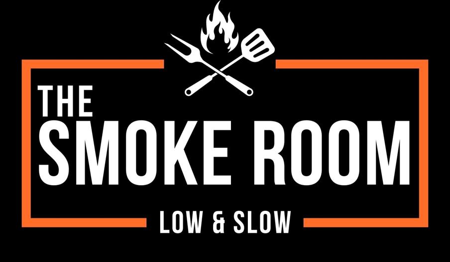 Logo for "The Smoke Room" with the tagline "Low & Slow," featuring a barbecue fork and spatula crossed over a flame, framed by an orange border on a b