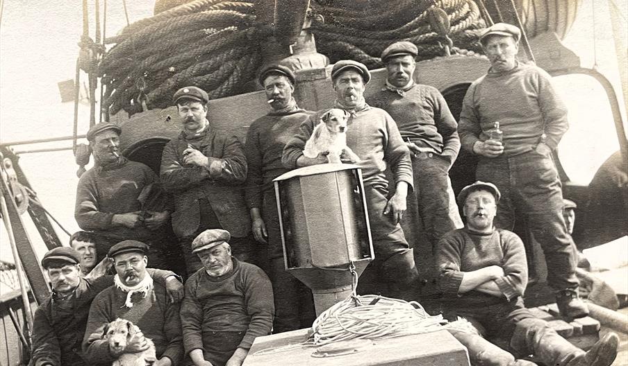 Black and white photograph of a trawler crew posing for a photograph on the deck of their vessel