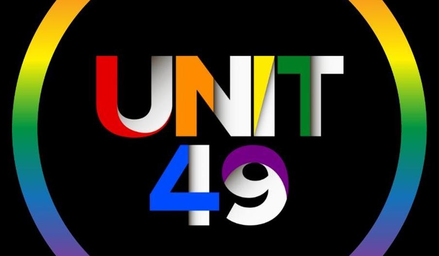 A rainbow coloured circle on a black background, with rainbow text on the inside that reads 'Unit 49'.