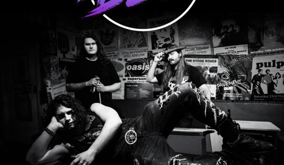 Black and white poster for a rock concert featuring the band Dead in Blue; three band members pose in a grungy room with band posters on the wall. Eve