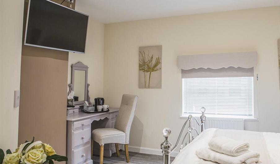 Bedroom with silver bed, desk and wall mounted TV