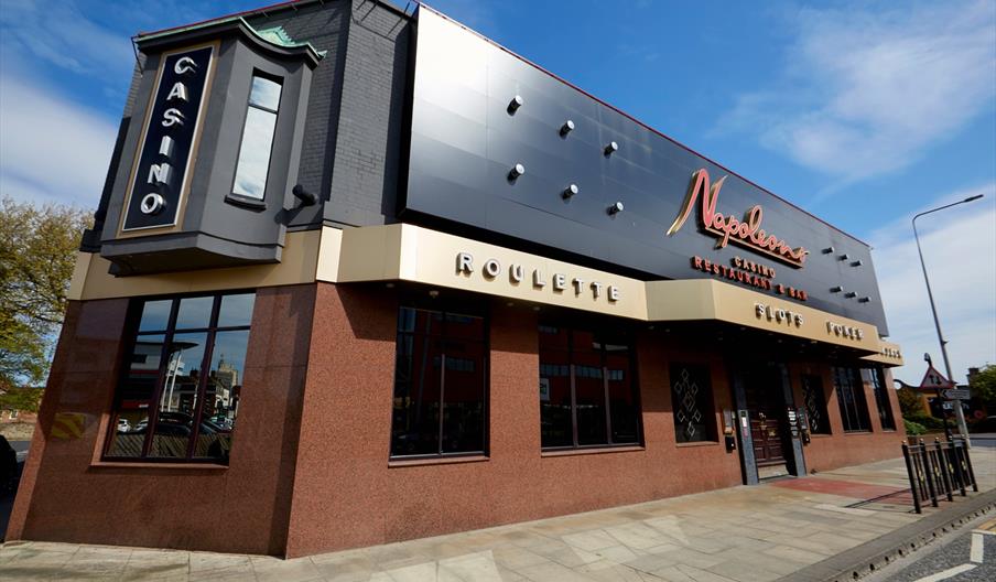 The outside of Napoleons Casino, a red and black modern building with a bright red logo above the double door entrance.