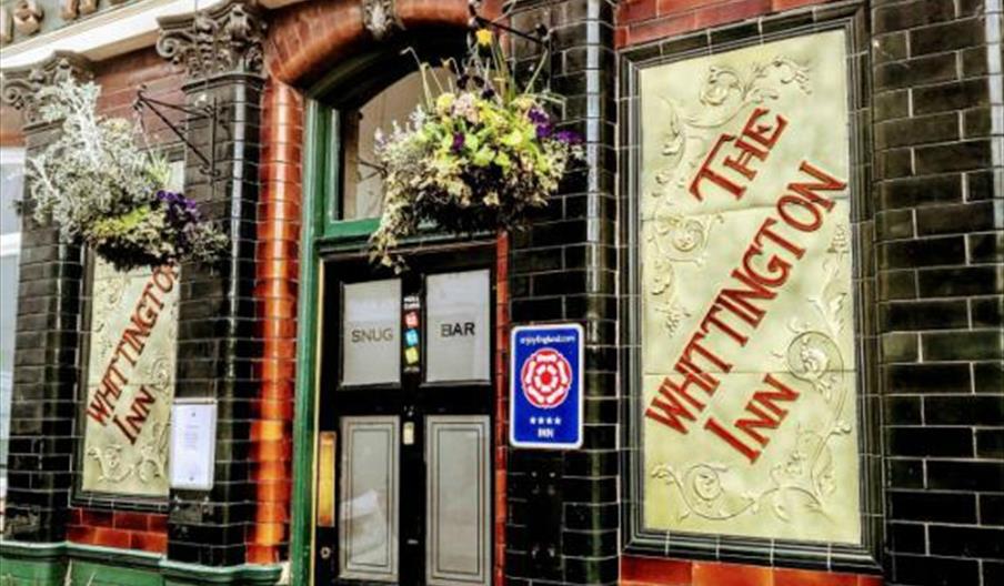 Outside of buidling with green and black, gold sign and black door.