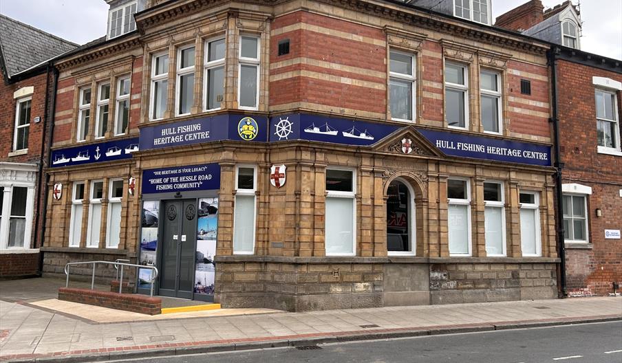 A historic two-story brick building the Hull Fishing Heritage Centre with a sign reading "Hull Fishing Heritage Centre" above the main entrance. The b