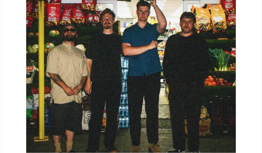 A promotional poster featuring four men standing side by side in front of a grocery store, with the event name "GAWLD" in large blue letters above, an