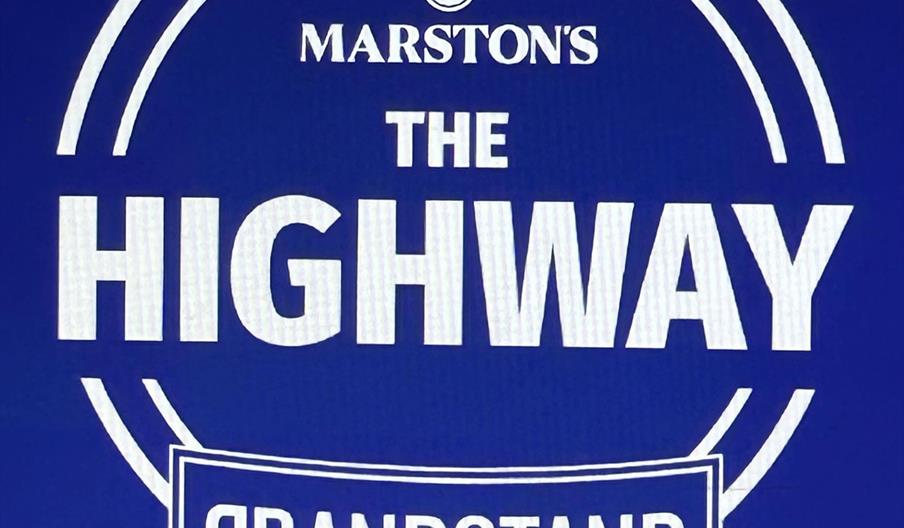 White text on a blue background displaying the words "Marston's The Highway Grandstand" inside a circular and rectangular outline.