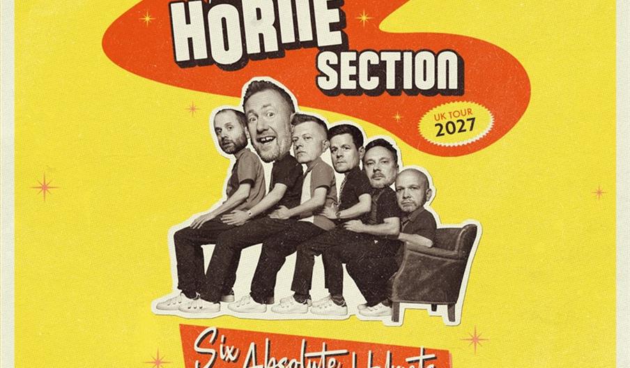 A retro-style poster features five men with oversized, collage-style heads sitting in a row on each other's laps in a single armchair against a yellow