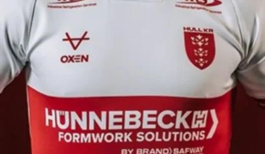 A person wearing a white rugby jersey with red accents and multiple sponsor logos, including Hünnebeck Formwork Solutions across the chest and the Hul