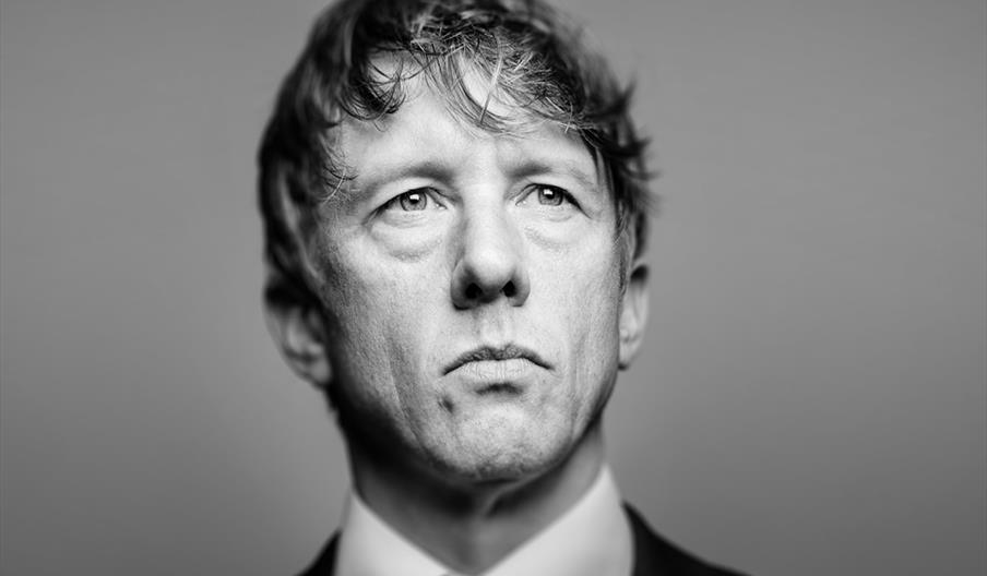 Black and white promotional poster featuring Johnathan Pie looking serious in a suit and tie, with large text above reading "The End of the World Acco