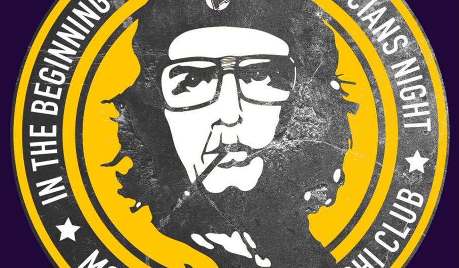 A circular logo featuring a black and white stylized portrait of a person with long hair, glasses, and a beret, with the text "In the beginning there