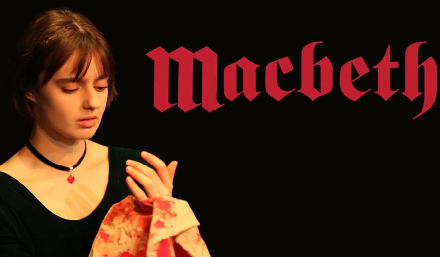 A young woman in a dark dress and choker looks down at her hand, holding a blood-stained cloth, with the word "Macbeth" in large red Gothic letters on