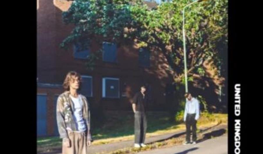 Three people stand on a sunny sidewalk in front of a brick building and leafy trees, with "Mouth Culture" written at the top in large, stylized font a