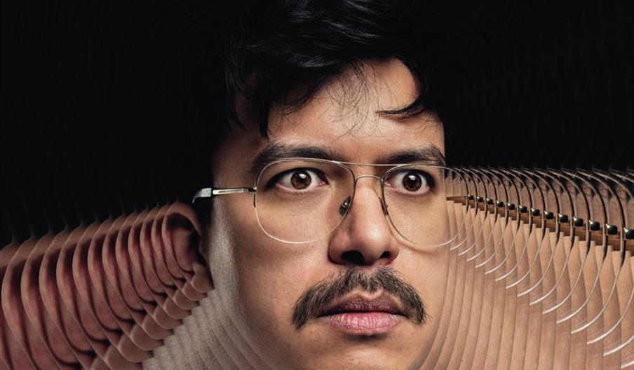 Phil Wang is shown with his face digitally manipulated to create a swirling, mirrored distortion effect that repeats sections of his face outward in a