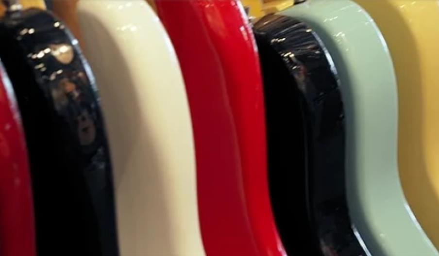Close-up of a row of colourful electric guitars displayed in Gough & Davy music store in Hull, showcasing a range of instruments available for musicia